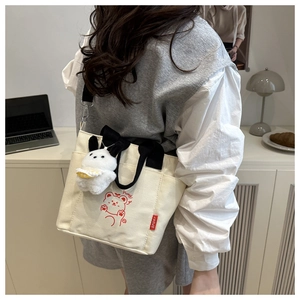 Detail of canvas tote bag with red bear print and white plush bunny charm accessory