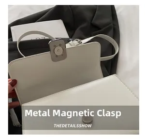 Détail du fermoir magnétique argenté sur un sac bandoulière en similicuir blanc