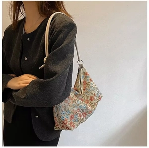 Close-up of vintage floral canvas shoulder bag with ethnic patterns on a model