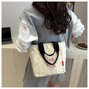 Detail of canvas tote bag featuring red cartoon bear print and black adjustable strap