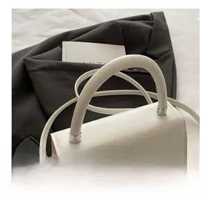 Detailansicht der weißen quadratischen Tasche mit silbernem Strassstern und bequemem Griff