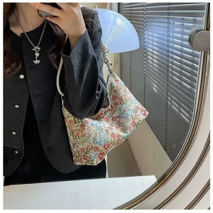Close-up of floral canvas hobo bag with white rope handle and silver heart pendant