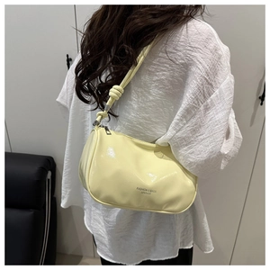 Gedetailleerd achteraanzicht van een beige laksleren tas met stijlvolle schouderband met knoop