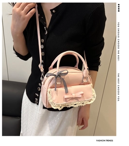 Pink faux leather bowling bag with lace trim and bow detail shown on a model