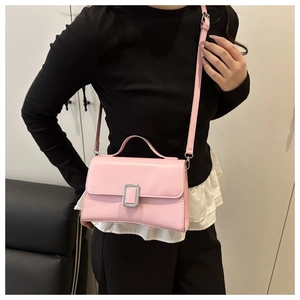 Détail du sac à bandoulière en similicuir rose avec boucle argentée porté par un mannequin
