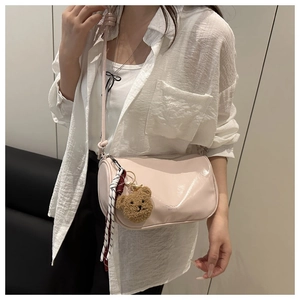 Detail van lichtroze crossbodytas met schattige pluche beer hanger en gestreepte sjaal