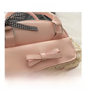 Detail of pink faux leather bag featuring a lace hem and checkered ribbon handle