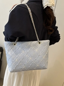 Chic light blue quilted tote bag with floral texture and metal chain shoulder strap