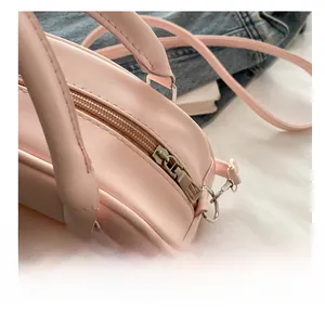Close-up of a pink faux leather shell bag showing smooth metal zipper and fine stitching