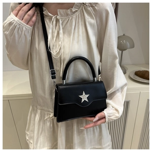 Detail der glänzenden schwarzen Handtasche mit Silberstern in minimalistischem Design