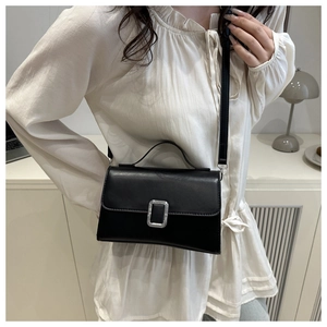 Détail du sac à bandoulière carré en cuir noir avec boucle argentée et poignée