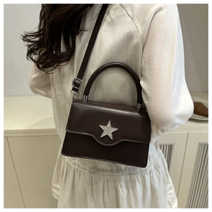 Detail der dunkelbraunen quadratischen Tasche mit Stern-Strass-Schnalle zum weißen Kleid