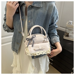 Lace detail and bow decoration on cream white crossbody bag shown on a model