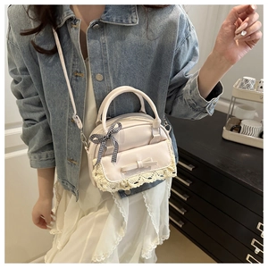 Close-up of cream Boston bag with delicate lace, bow detail and checkered ribbon
