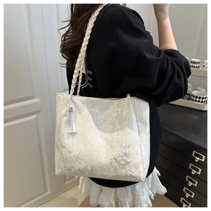Detail of white lace tote bag with butterfly embroidery and woven shoulder strap
