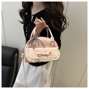 Close-up of pink Boston bag featuring lace pocket, bow detail and checkered ribbon handle