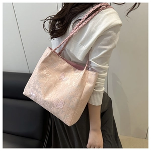Detailed view of light pink floral tote bag with butterfly embroidery and braided straps