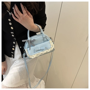 Detail of light blue handbag featuring white lace trim and a delicate bow decoration