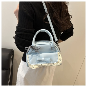 Light blue bowling bag with white lace and bow details shown worn as a crossbody