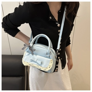 Detail of light blue crossbody bag with lace pocket and black-white checkered ribbon