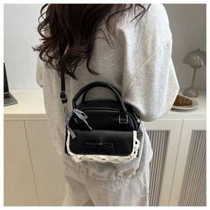 Detail of black bow handbag with lace trim and checkered ribbon in a lifestyle setting
