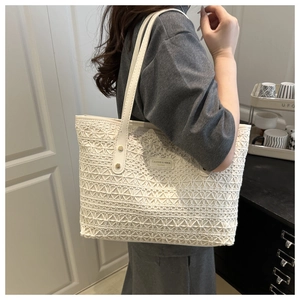 Detail of white lace crochet tote bag with fashion label and long shoulder straps
