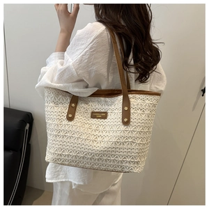 Detailed shot of white lace crochet tote bag with brown faux leather trim and brand label