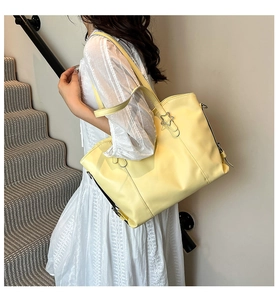 Detail of light yellow leather tote bag featuring a star-shaped metal buckle on the strap