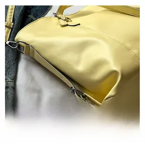 Close-up of yellow faux leather tote with fine stitching and silver metal hardware details