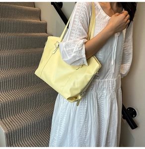 Detail of soft yellow faux leather tote bag with silver star charm and side tie straps