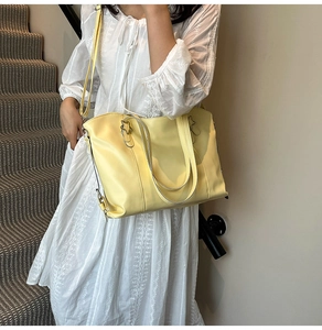Detail view of large pale yellow leather tote bag showing texture and side zipper