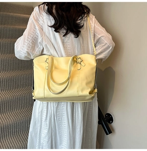 Detail of light yellow soft leather tote bag featuring star-shaped metallic accents