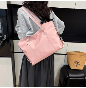 Pink faux leather tote bag with unique star-shaped metal ring detail worn by model