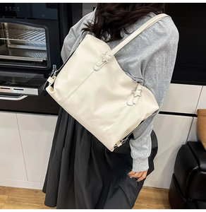 Detail of soft cream tote bag featuring a silver star buckle on the shoulder strap