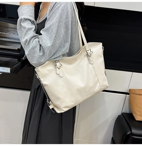 Detail of silver star metal buckle and soft cream leather texture on the tote bag