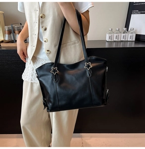 Detail view of large black leather tote bag featuring stylish silver star metal buckles