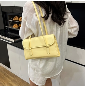 Side view of yellow faux leather shoulder bag with accordion pleats on female model