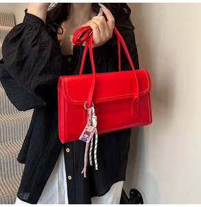 Detailed view of red baguette bag with scalloped stitching and woven charm