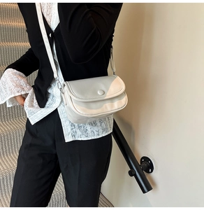 Close-up of minimalist cream-white crossbody bag featuring a subtle pleated leather texture