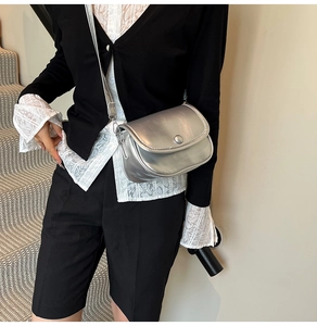 Detail of silver crossbody bag with round decorative buckle on a model for daily commute