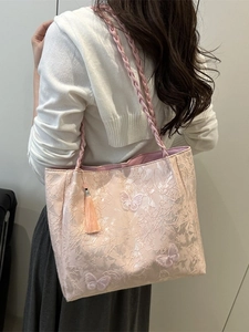 Pink canvas tote bag with butterfly embroidery and tassel shown from a side view
