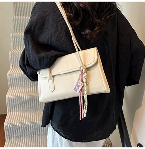 Detail of off-white rectangle shoulder bag with woven rope charms and cartoon pendant