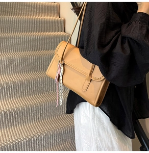 Detail of camel leather baguette bag with side lanyards on a striped staircase