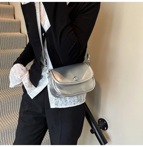 Close-up of a silver metallic crossbody bag featuring a magnetic flap and D-ring detail