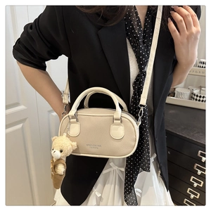 Detail of off-white lychee leather handbag with cute bear charm and silver logo