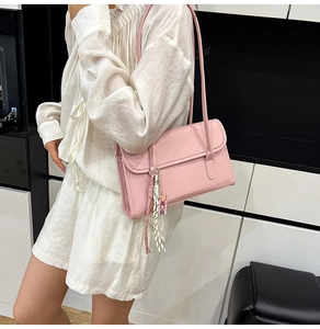 Detail of pink leather baguette bag featuring fine stitching and decorative charm