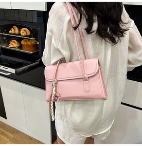 Pink French baguette shoulder bag with tassel charm styled on a white shirt