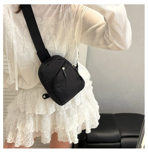 Détail du sac de poitrine noir en nylon avec plusieurs zips et bandoulière large réglable
