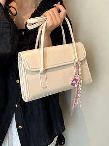 Minimalist creamy white baguette bag with double handles and trendy decorative charm