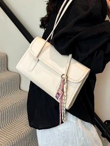 Off-white leather baguette shoulder bag with hand-stitched edges and colorful bag charms